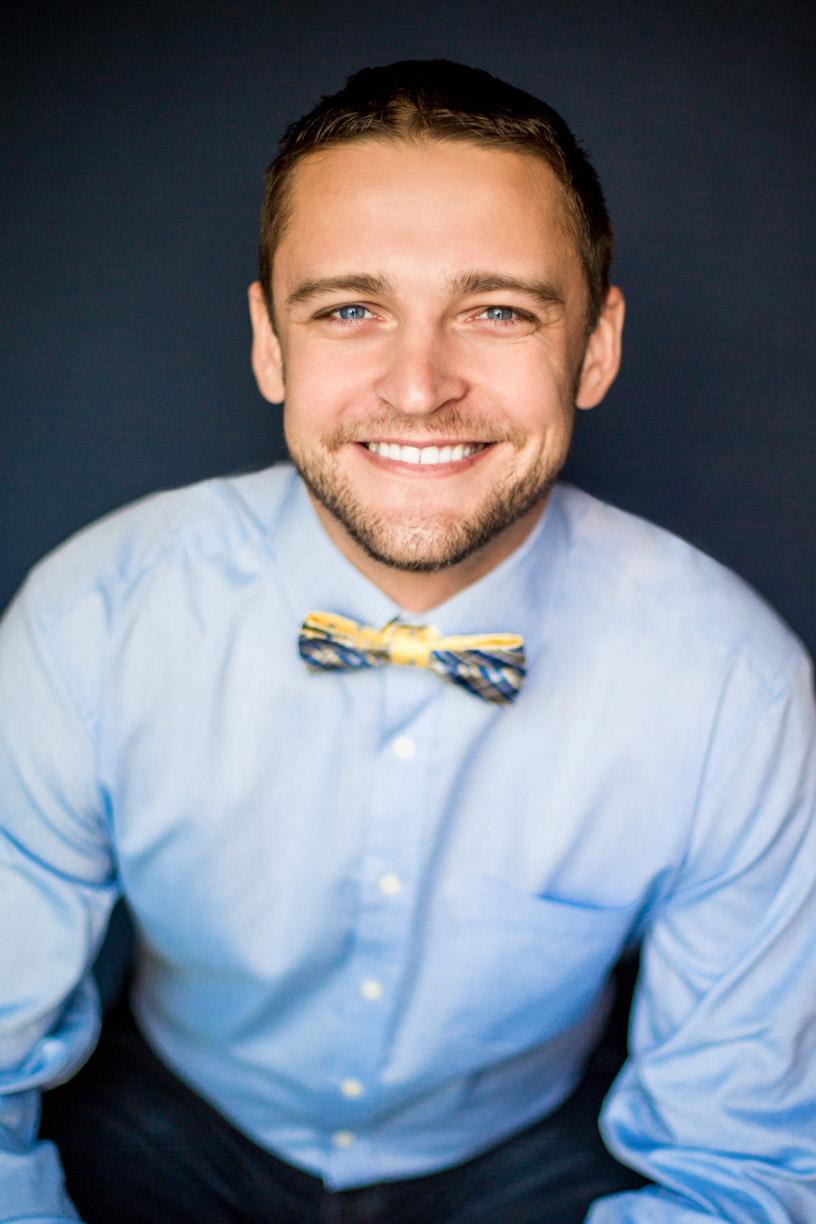 Headshot of a man waring blue shirt and a bow tie